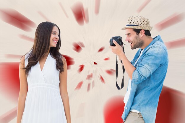 Красивый хипстер фотографирует симпатичную девушку на фоне любовного рисунка сердца