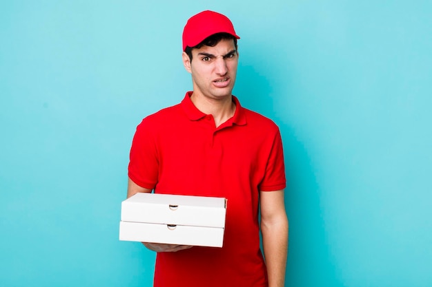 Handsome hispanic man feeling puzzled and confused delivery pizza concept