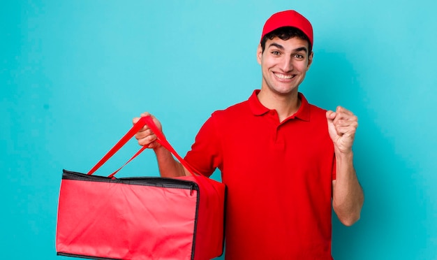 Handsome hispanic man feeling shockedlaughing and celebrating success delivery pizza concept