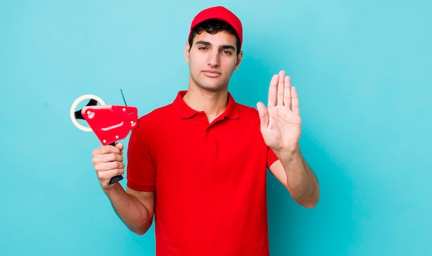 Handsome hispanic man looking serious showing open palm making stop gesture packer concept