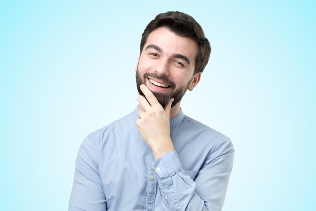 Handsome hispanic man in shirt looking at camera standing on bright blue background