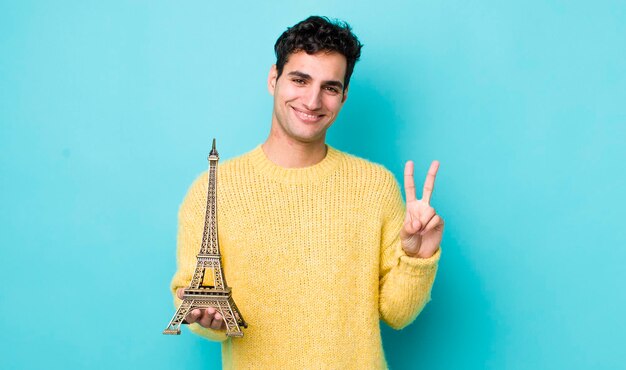 Handsome hispanic man smiling and looking friendly showing number two france concept