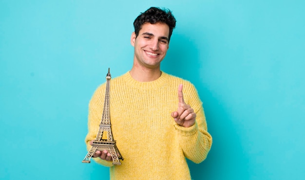 Handsome hispanic man smiling proudly and confidently making number one france concept