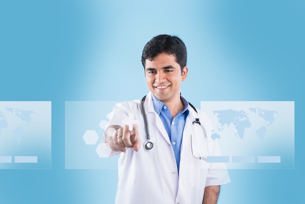 Handsome Indian Male Doctor touching virtual screen with index finger. standing isolated over blue background