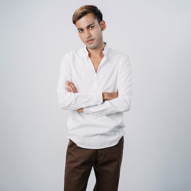 Foto il giovane uomo d'affari indiano bello ha incrociato le braccia in piedi isolato muro grigio