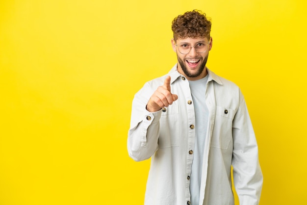 Handsome over isolated blue wall shaking hands for closing a good deal