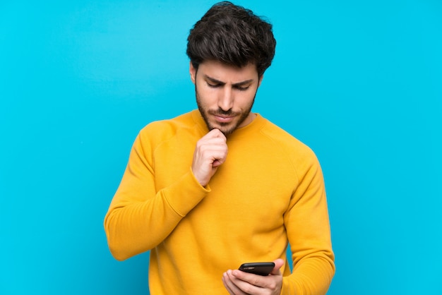 Handsome over isolated blue wall thinking and sending a message