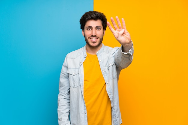 Handsome over isolated colorful wall happy and counting four with fingers