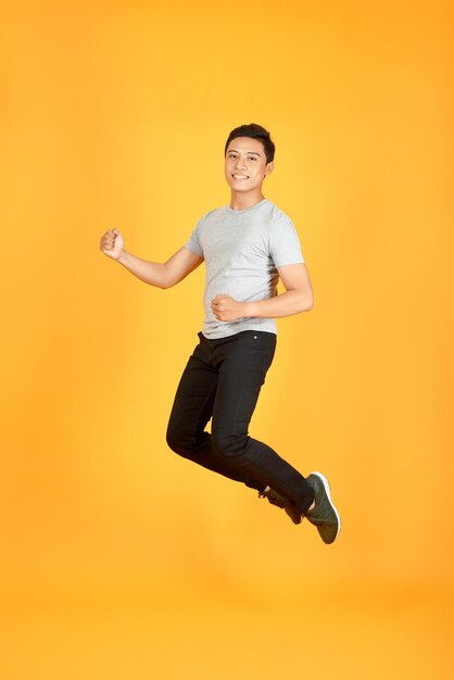 Handsome jumping asian man on color background