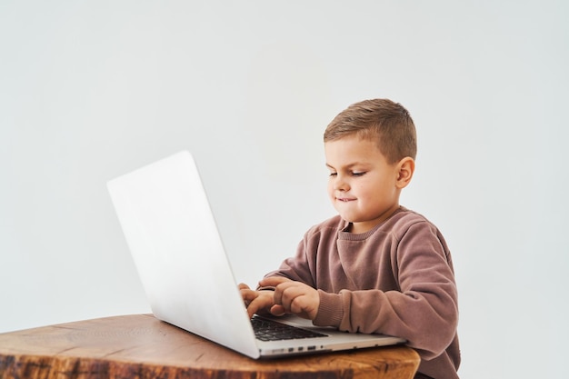 Handsome kid use laptop and look at camera watch virtual lecture and tutorial Elearning and knowledge Preparation for lesson and studying online on white background