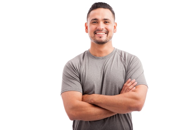 Handsome Latin athlete in a sporty outfit with his arms crossed and smiling on a white background