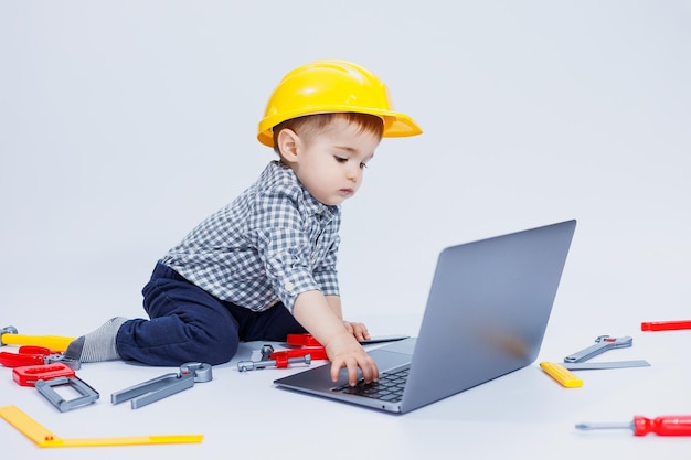 A handsome little boy 23 years old in a shirt on a white background is looking at a laptop A child is playing with a portable laptop