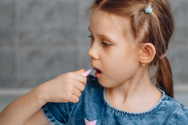 A handsome little girl opens her mouth wide and brushes her teeth The concept of children's oral care