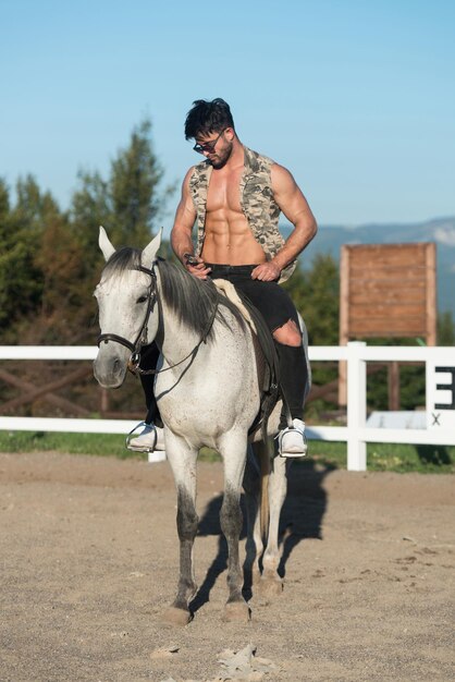 Handsome Macho Man Cowboy Riding on a Horse  Background of Sky and Mountains