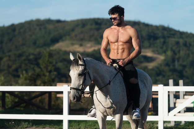 Handsome Macho Man Cowboy Riding on a Horse  Background of Sky and Mountains