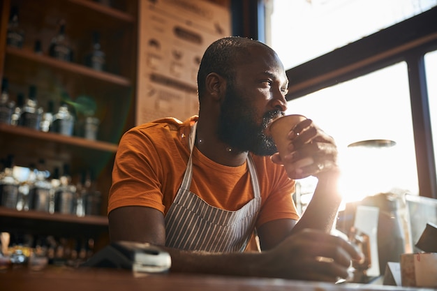 Handsome male bartender drinking coffee at work