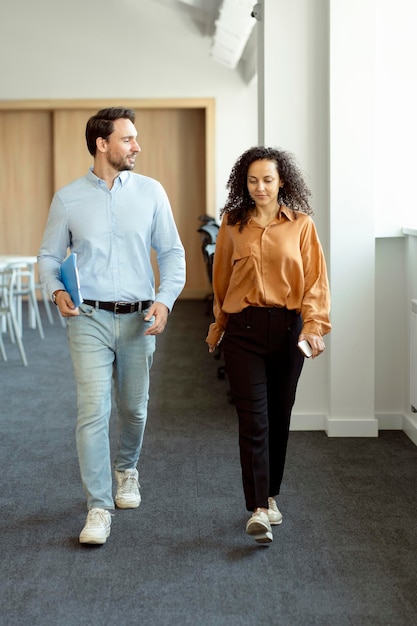 handsome male bearded manager and his female assistant walking around modern office talking