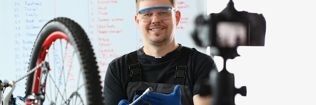 Handsome male blogger in bicycle repair shop