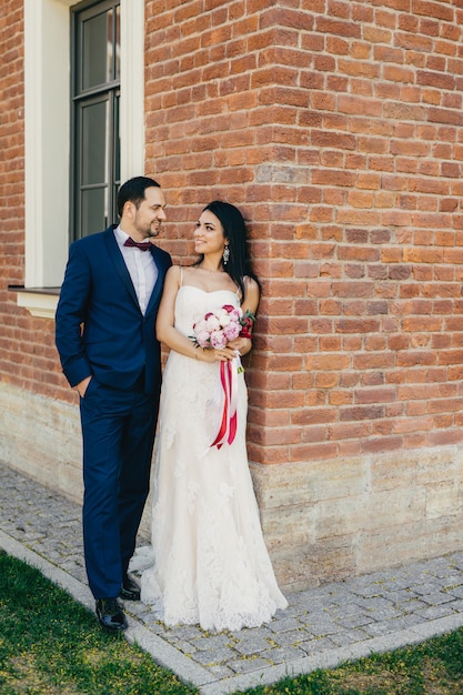 Handsome male bridegroom looks with great love at his bride