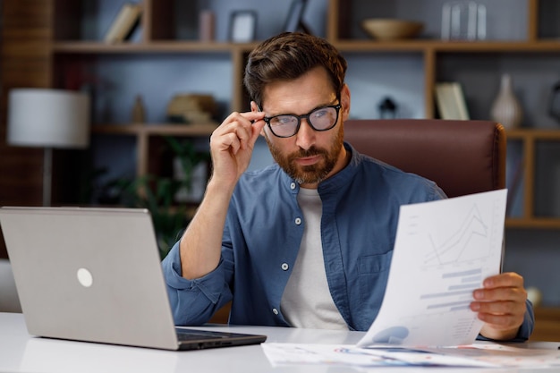 Handsome male businessman manager working behind a laptop in a stylish home office Remote work at home Portrait of a successful freelancer