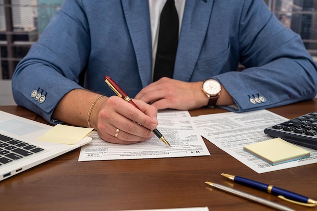 handsome male businessman sitting at the table and filling out US tax forms 1040. Concept of tax forms and businessman