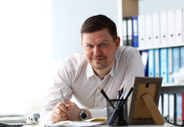 Handsome male clerk ar office working table looking in camera