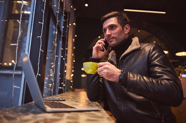 Красивый мужчина общается на смартфоне в кафе
