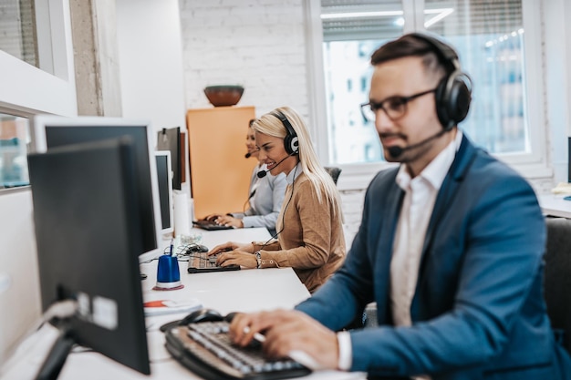 Photo handsome male customer service agent with headset working in call center.