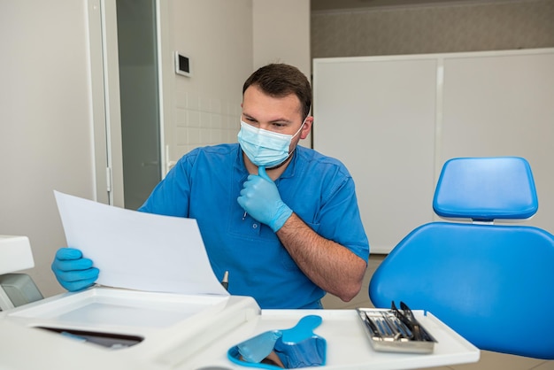 Handsome male dentist in medical clothes treats his patients with dental problems Dental treatment concept