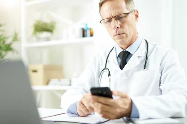 Handsome male doctor using cellphone at work