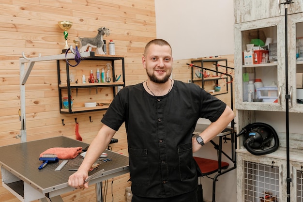 Toelettatore maschio bello con attrezzatura professionale sul suo posto di lavoro nel salone di toelettatura per animali domestici