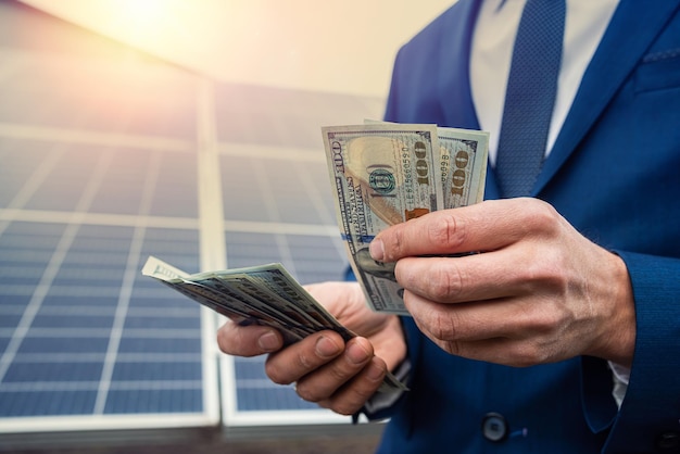 Handsome male hands holding dollars to pay for working with solar panels