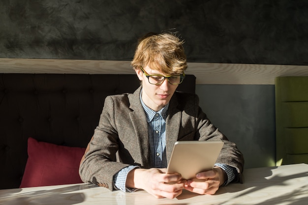 Handsome male reads tablet pc at cafe