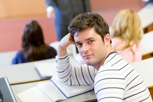 Handsome male student smiling at the camera during an university lesson