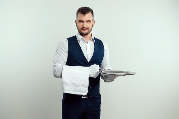 Photo handsome male waiter, in white shirt, holding a silver tray. the concept of serving staff serving customers in a restaurant.