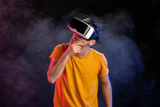 Handsome male wearing virtual reality headset on dark surface