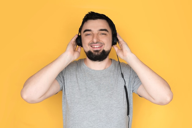 Фото Красивый мужчина с наушниками на голове, слушая музыку и улыбаясь.