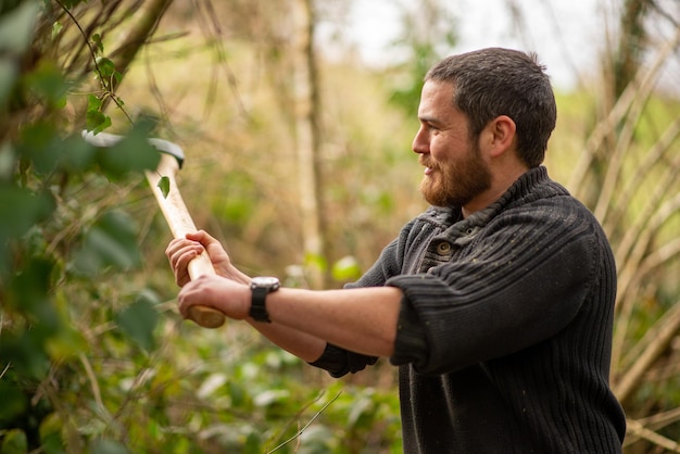 Handsome man 30 years old cuts a tree with an ax