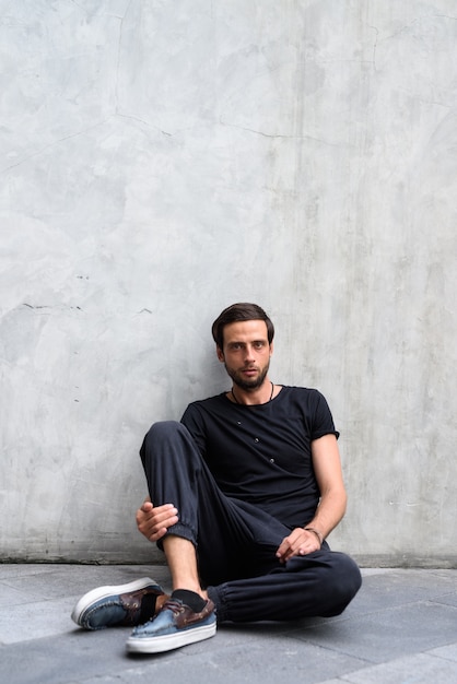 Handsome man against concrete wall in the streets outdoors