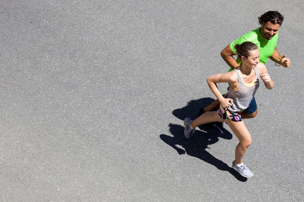 Handsome man and beautiful woman jogging together on street at sunny day