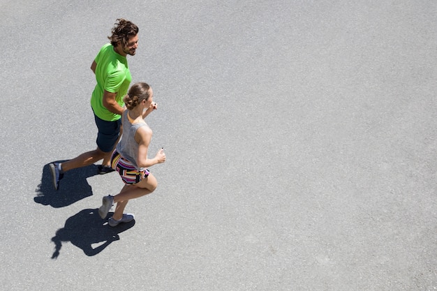 Handsome man and beautiful woman jogging together on street at sunny day