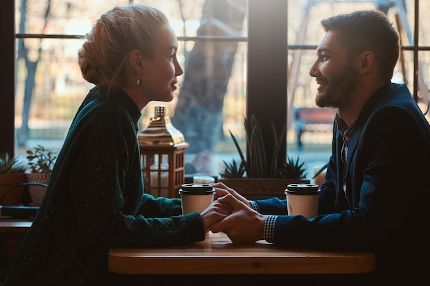 Handsome man and beautiful woman spend their time together while drinking coffee at cafeteria.