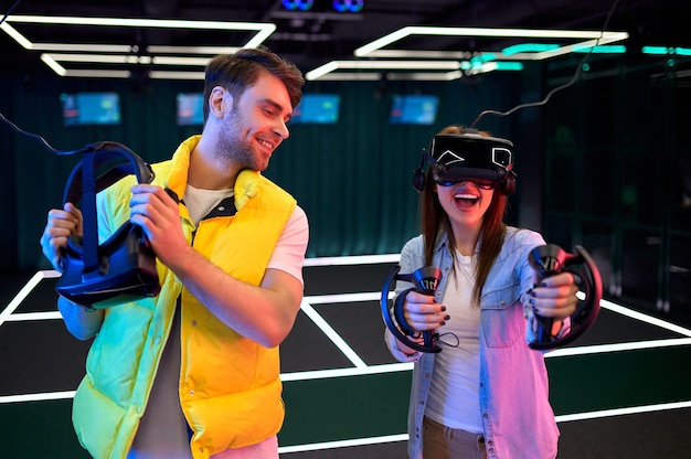 Handsome man and beautiful young woman with glasses of virtual reality. VR, games, entertainment, future technology concept. Couple with virtual reality headset having fun together.