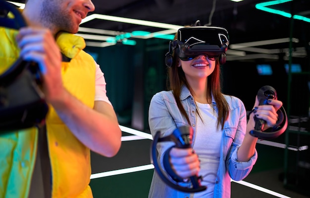Handsome man and beautiful young woman with glasses of virtual reality. VR, games, entertainment, future technology concept. Couple with virtual reality headset having fun together.