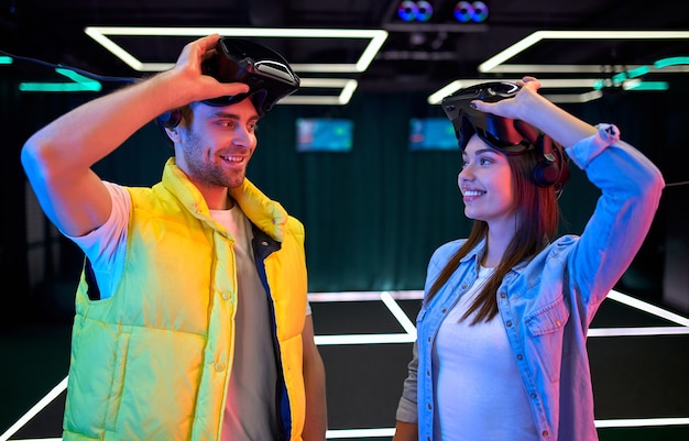 Handsome man and beautiful young woman with glasses of virtual reality. VR, games, entertainment, future technology concept. Couple with virtual reality headset having fun together.