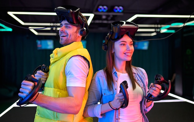 Handsome man and beautiful young woman with glasses of virtual reality. VR, games, entertainment, future technology concept. Couple with virtual reality headset having fun together.