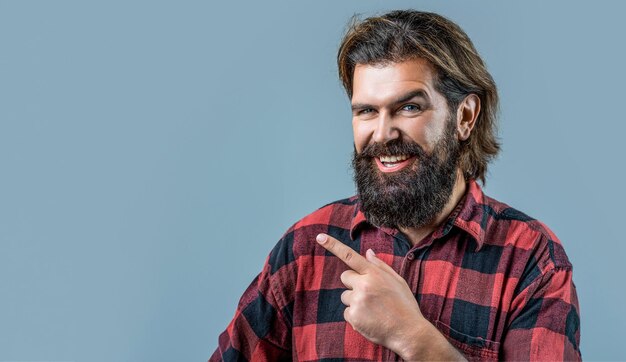 Handsome man big smile on face pointing with hand and finger to the side Portrait of attractive glad cheerful man manager demonstrating ad copy space isolated over gray color background