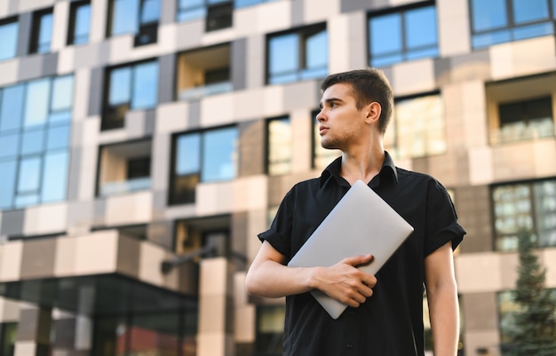 Uomo bello in una camicia nera con un computer portatile