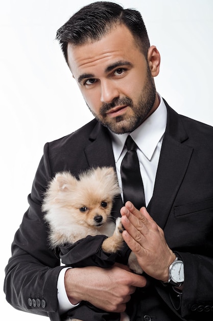 Handsome man in black suit holds pomeranian dog. Spitz. people and pets