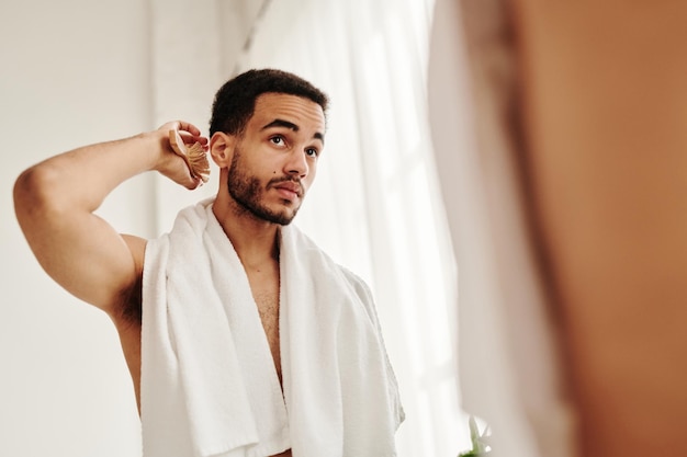 Handsome man brushing his hair